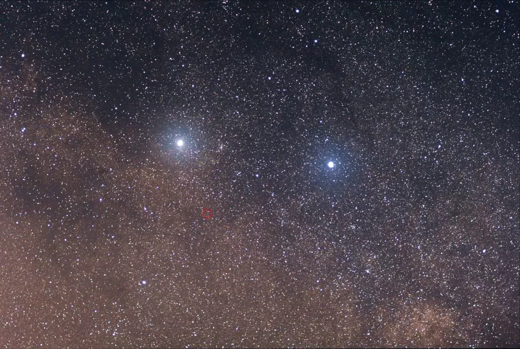 Dvije sjajne zvijezde su (lijevo) Alpha Centauri i (desno) Beta Centauri. Slaba crvena zvijezda u središtu crvenog kruga je Proxima Centauri. Snimljeno objektivom Canon 85 mm f / 1,8 s naslaganih 11 okvira, svaki kadar izložen 30 sekundi. Izvor: Skatebiker / Wikimedia Commons.