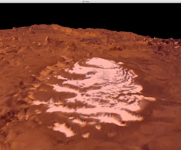 Pogled na južnu polarnu kapu Marsa. Bijeli led je kapa zaostalog ugljičnog dioksida koja se nalazi na vrhu i štiti mnogo deblje CO2-ledenjake. Okolni teren sastoji se od crvene prašine koja prekriva planine u pozadini i 4 kilometra debele H2O-ledene kape (©NASA).