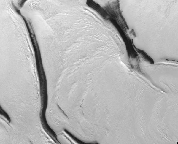 Pogled odozgo prema dolje na najveći CO2-ledenjak na južnoj polarnoj kapi Marsa. Tamne trake su granice bazena koje ograničavaju ledenjake, široke 40 kilometara (©NASA/MSSS).