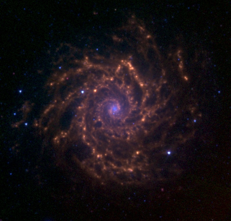 Ova slika prikazuje M74 kako ju je snimio Spitzer svemirski teleskop u infracrvenom zračenju. Plave boje predstavljaju emisiju zvijezda od 3.6 mikrometara. Zelena i crvena predstavljaju policikličke aromatske ugljikovodike i emisiju prašine na 5.8 odnosno 8.0 mikrometara (©NASA).