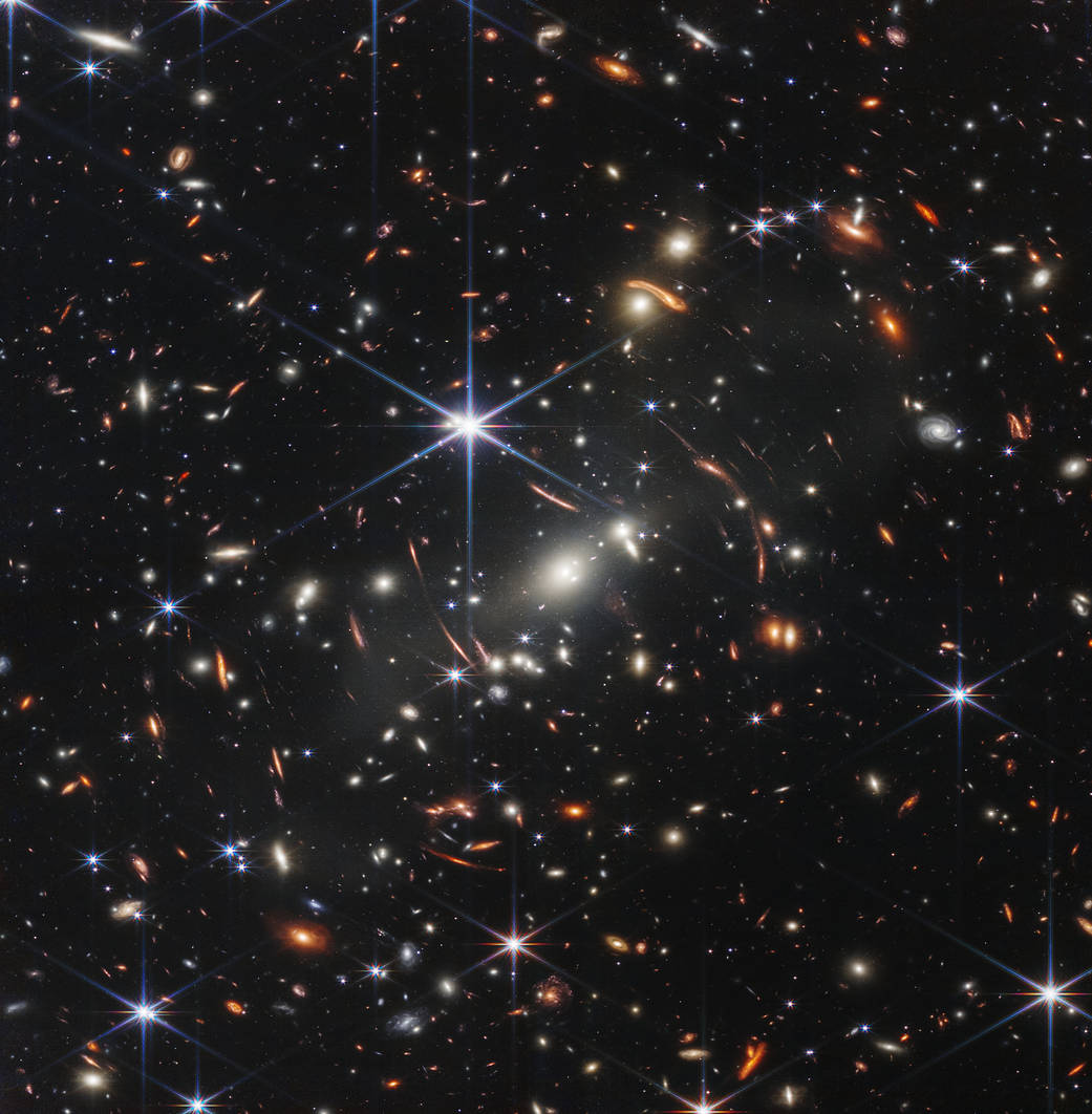 Prva objavljena slika prikazuje jato galaksije SMACS 0723 – kakvo je bilo prije 4.6 milijardi godina – koje je 'iskorišteno' kao gravitacijska leća kako bi se dobilo uvide u udaljenije galaksije svemira, sežući gotovo do samih početaka (do otprilike 13/13.5 milijardi godina). Veoma svjetle točke koje dominiraju slikom zvijezde su unutar naše galaksije koje su se našle 'na Webbovom putu', dok najudaljenije galaksije vidimo kao 'sićušne' izvore svjetlosti u daljini. Nova slika tako je najdublji i najoštriji pogled u povijest našega svemira do sada (©NASA, ESA, CSA, STScI).