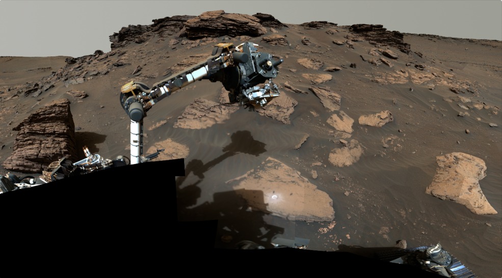 NASA-in rover Perseverance tijekom korištenja svoje robotske ruke na površini Crvenog planeta. Sastavljen od više slika ovaj mozaik prikazuje naslagane sedimentne stijene na litici nekadašnje delte, a moguće je vidjeti i 'kružnu mrlju' koja predstavlja mjesto na kojem je rover 'zagrebao' površinu kako bi analizirao sastav stijene (©NASA/JPL-Caltech/ASU/MSSS).