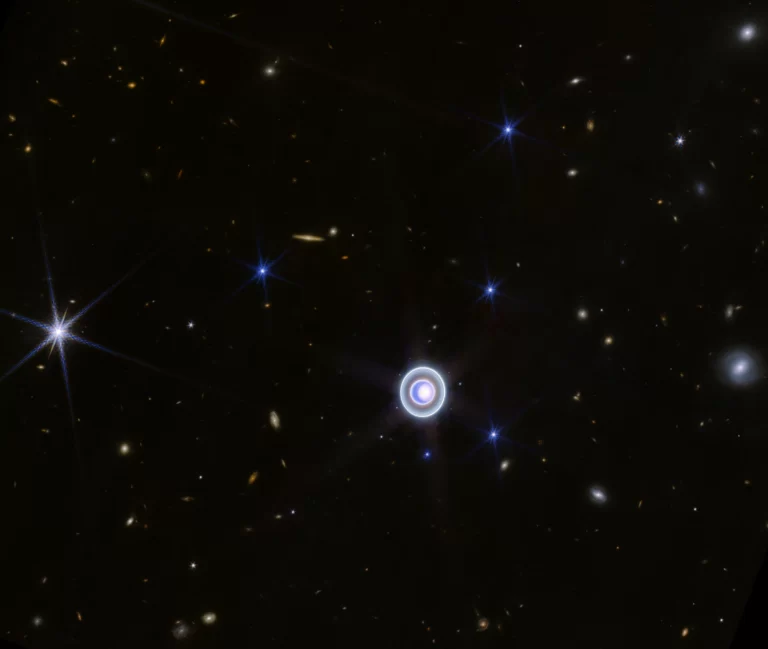 Ova širokokutna slika Urana snimljena NIRCam-om (Near-Infrared Camera) na NASA-inom svemirskom teleskopu James Webb prikazuje planet usred razasutih udaljenih galaksija u pozadini. Na ovoj slici prikazano je i 14 od ukupno 27 mjeseca planeta. NASA.