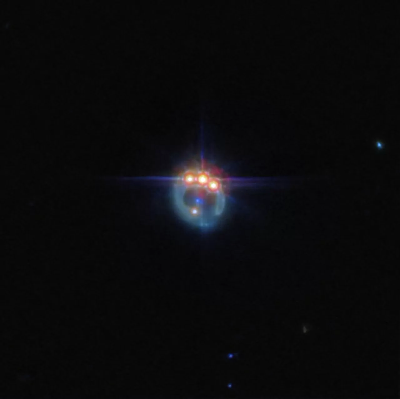 Fotografija galaksije iskrivljene gravitacijskom lećom u prigušeni prsten. Na vrhu prstena nalaze se tri vrlo svijetle točke s difrakcijskim šiljcima koji se protežu iz njih, smještene jedna pored druge: ovo su kopije jednog kvazara u lećastoj galaksiji, duplicirane gravitacijskom lećom. U središtu prstena, eliptična galaksija koja vrši lećenje pojavljuje se kao mala plava točka. Pozadina je crna i prazna. Kredit: ESA/Webb, NASA & CSA, A. Nierenberg.
