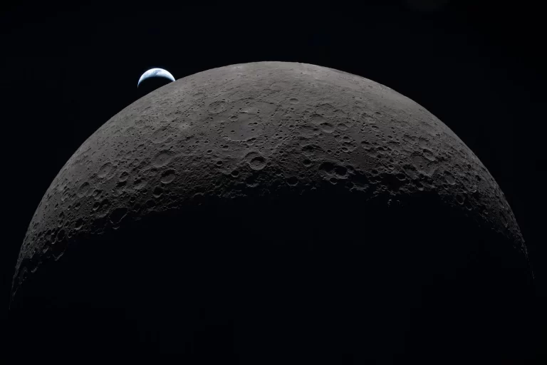 Na ovoj fotografiji koju je posada misije Artemis II snimila 6. travnja 2026. tijekom leta oko dalje strane Mjeseca vidi se Zemlja kako zalazi iza njegova zakrivljenog obzorja. Uz vidljivi dio Mjesečeve površine raspoznaje se bazen Orientale, dok se Hertzsprung nazire kao dva blaga koncentrična prstena koje presijeca mlađi krater Vavilov. Nizovi udubina sekundarni su lanci kratera nastali od materijala izbačenog pri golemom udaru koji je oblikovao Orientale. Tamni dio Zemlje uronjen je u noć, a na osvijetljenoj strani vide se oblaci iznad Australije i Oceanije. Zasluge: NASA