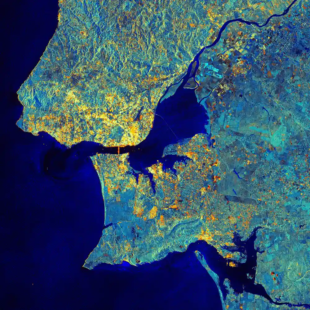 Ova radarska snimka satelita Sentinel-1A prikazuje metropolitansko područje Lisabona, glavnog grada Portugala. Iz gornjeg desnog kuta ulazi rijeka Tejo. Rijeka teče prema zapadu kroz Portugal i ulijeva se u Atlantski ocean kod Lisabona. Njezin estuarij, vidljiv u središtu slike, prirodni je rezervat i Ramsarsko močvarno područje od međunarodne važnosti. S prostranim muljevitim pličinama, slanim močvarama, tršćacima i umjetnim solanama, to je područje važno za oko 16 vrsta vodenih ptica koje ondje zimuju ili se zaustavljaju tijekom selidbe, za brojne vrste ptica koje se ondje gnijezde te za europsku vidru. Izvan rezervata prisutni su ribolov, skupljanje školjkaša i poljoprivreda, što se vidi po geometrijskim oblicima poljoprivrednih parcela. Središte Lisabona nalazi se na sjevernoj obali rijeke Tejo, a na slici se prepoznaje po snažnim radarskim refleksijama zgrada i drugih građevina. Vidljive su i refleksije visećeg mosta koji povezuje Lisabon s Almadom na južnoj obali. Dalje prema istoku, iako manje jasno, nalazi se most Vasco da Gama, najdulji most u Europi, dug 17,2 kilometra. Izvor: podaci programa Copernicus / ESA (2014).