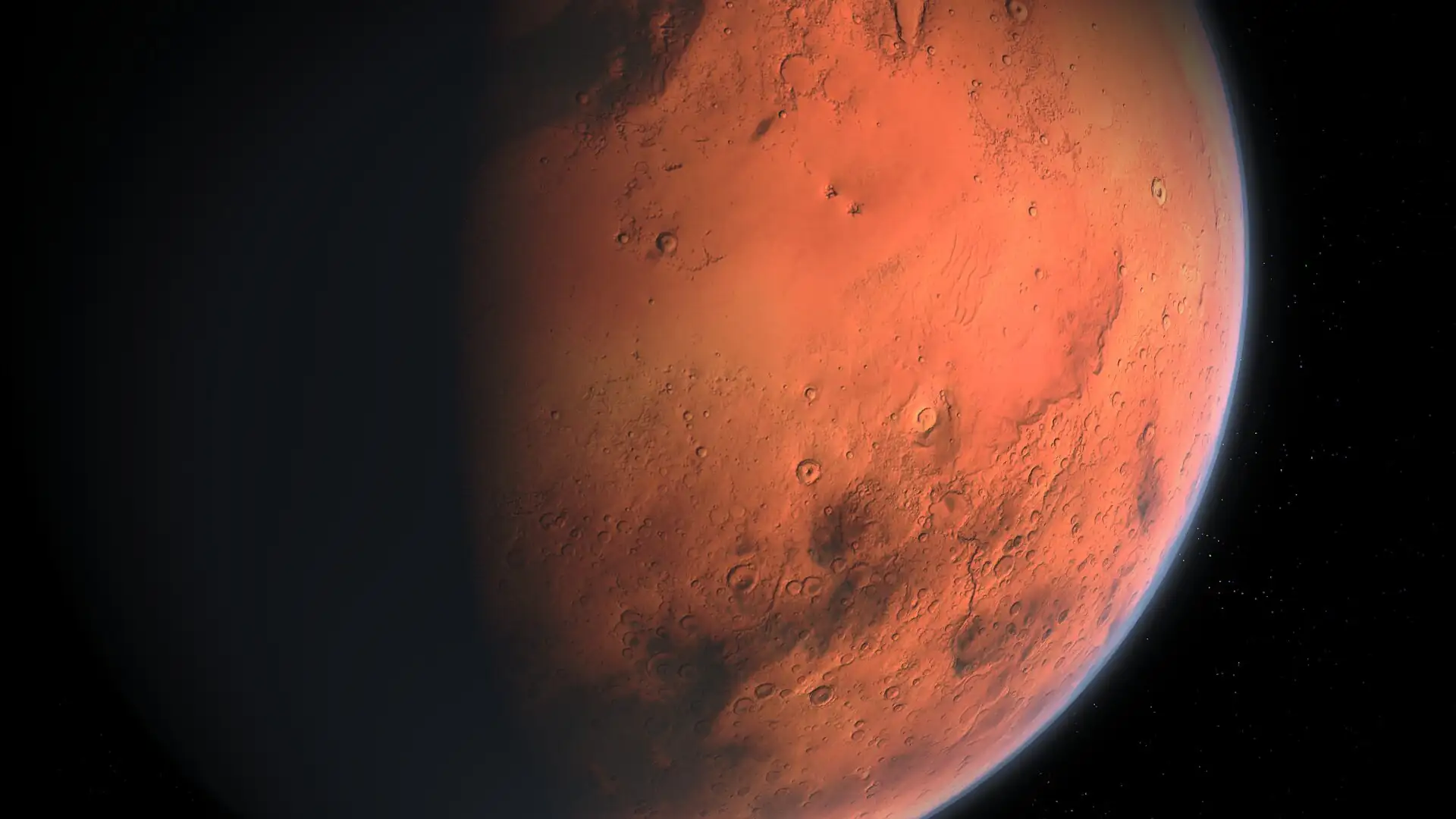 Mars prikazan iz svemira kao crvenkasto-narančast planet djelomično obavijen sjenom, s vidljivim kraterima i površinskim obilježjima na osvijetljenoj strani.
