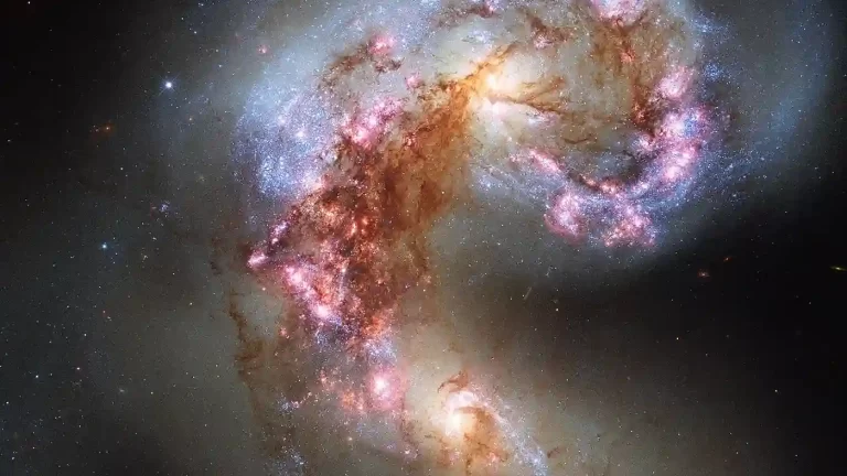 Hubbleova fotografija Galaksija Antena, para galaksija u sudaru, s plavim područjima mladih zvijezda, ružičastim oblacima plina i tamnim trakama prašine.