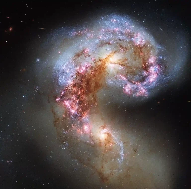 Hubbleova fotografija Galaksija Antena, para galaksija u sudaru, s plavim područjima mladih zvijezda, ružičastim oblacima plina i tamnim trakama prašine.