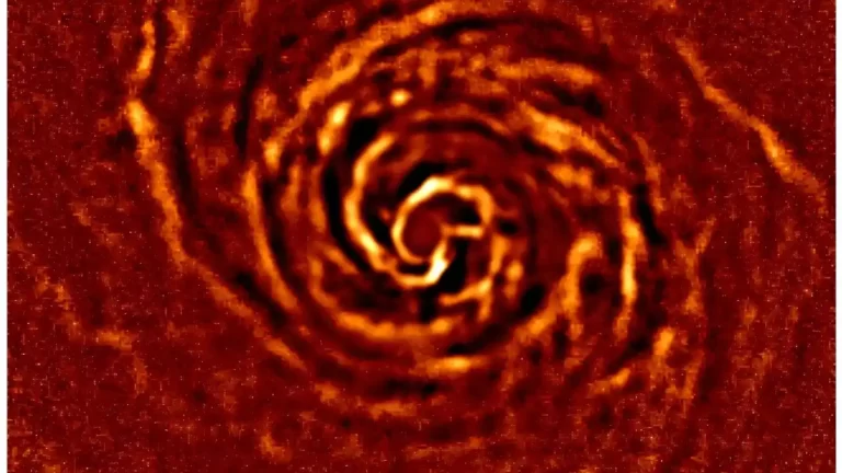 Protoplanetarni disk oko mlade zvijezde AB Aurigae prikazan u narančasto-crvenim tonovima, sa spiralnim strukturama prašine i plina oko središta diska.
