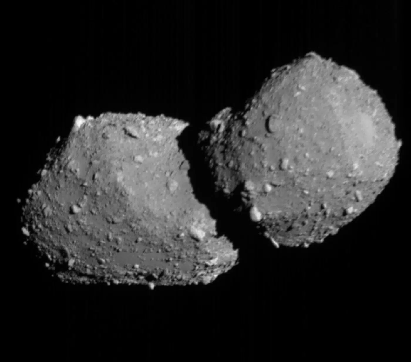 Crno-bijela snimka asteroida Torifune s dva spojena, nepravilno zaobljena dijela i kamenitom površinom na tamnoj pozadini svemira.