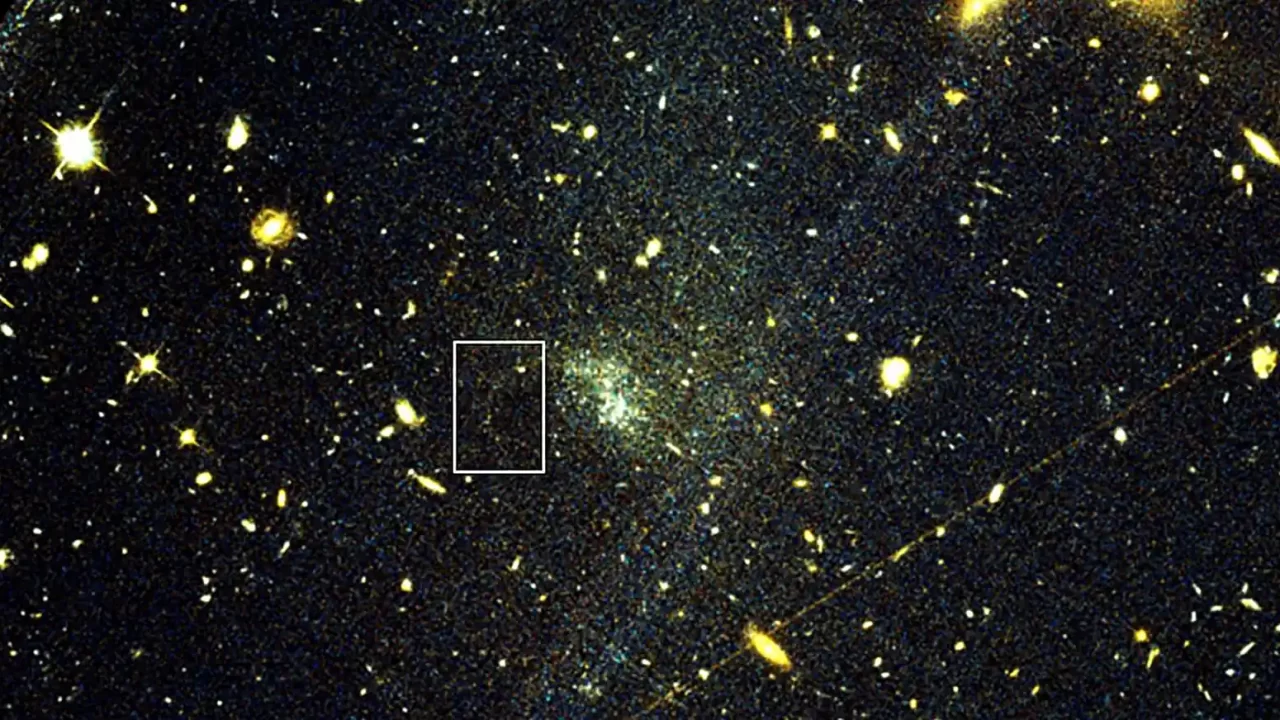 Hubbleova snimka prikazuje UGC9050-Dw1, slabu ultradifuznu galaksiju. U označenom području astronomi su pronašli izdužen niz zvijezda koji je nekoć pripadao kuglastom skupu. Oblik i položaj toka korišteni su za novu procjenu raspodjele tamne tvari u galaksiji. Zasluge: Hubble Space Telescope i Holm et al. (2026)