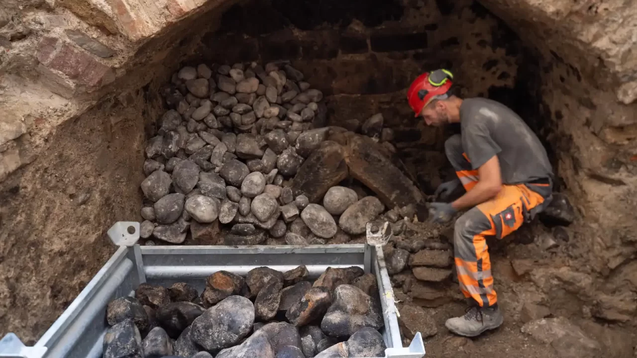 Arheolog uklanja kamenje iz komore srednjovjekovnog sustava grijanja u Baselu