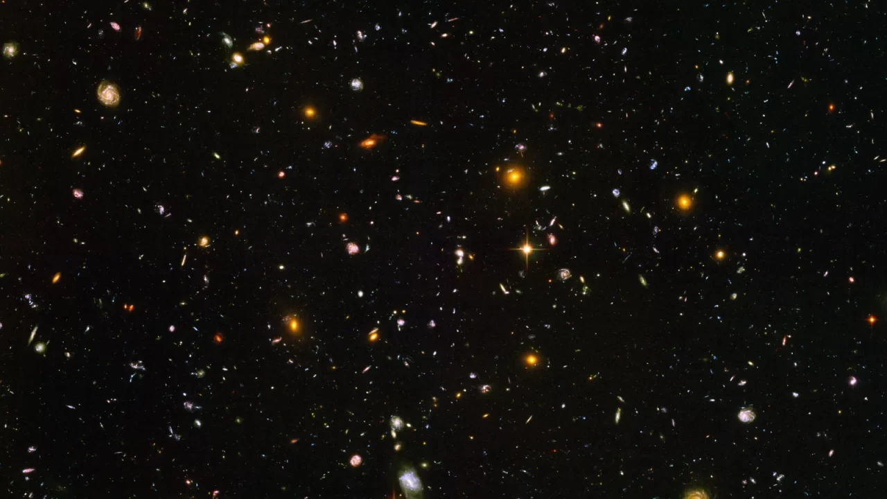 Mnogobrojne male galaksije različitih boja i oblika u tamnom Hubbleovu dubokom polju.