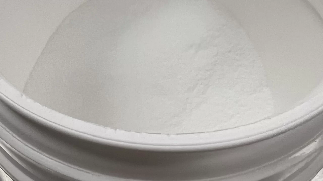 Bijeli prah kreatin monohidrata u otvorenoj plastičnoj posudi