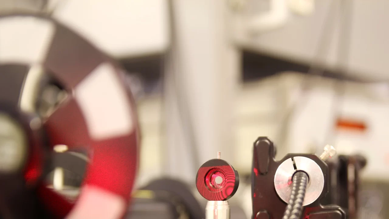 Crvena laserska svjetlost na optičkim elementima laboratorijskog postava.