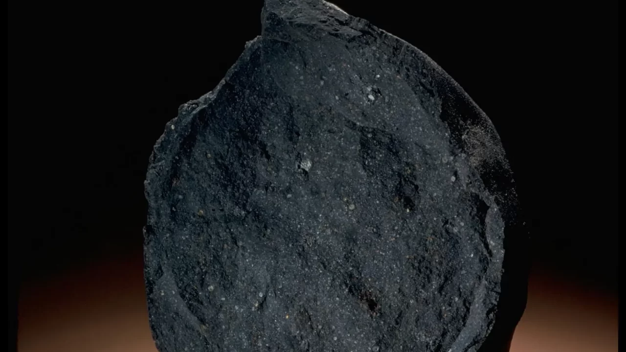 Tamni uzorak meteorita Murchison na osvijetljenoj podlozi i crnoj pozadini