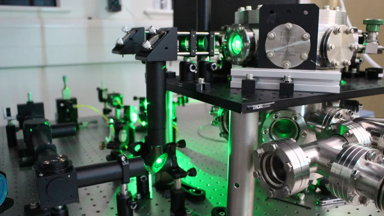 Laserska i optička oprema s vakuumskom komorom na laboratorijskom stolu.