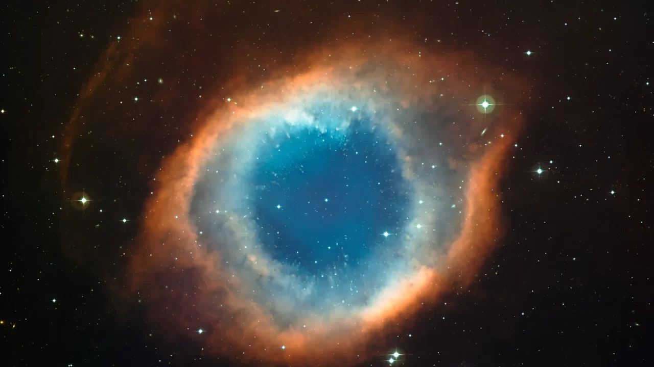 Planetarna maglica Helix s plavozelenim središtem i crvenkastim prstenom plina, okružena zvijezdama.