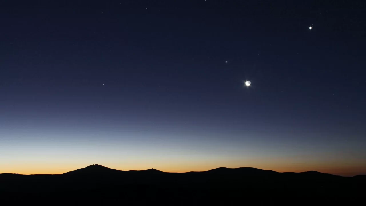 Mjesec, Venera i Jupiter na nebu iznad tamnog krajolika kod opservatorija Paranal.